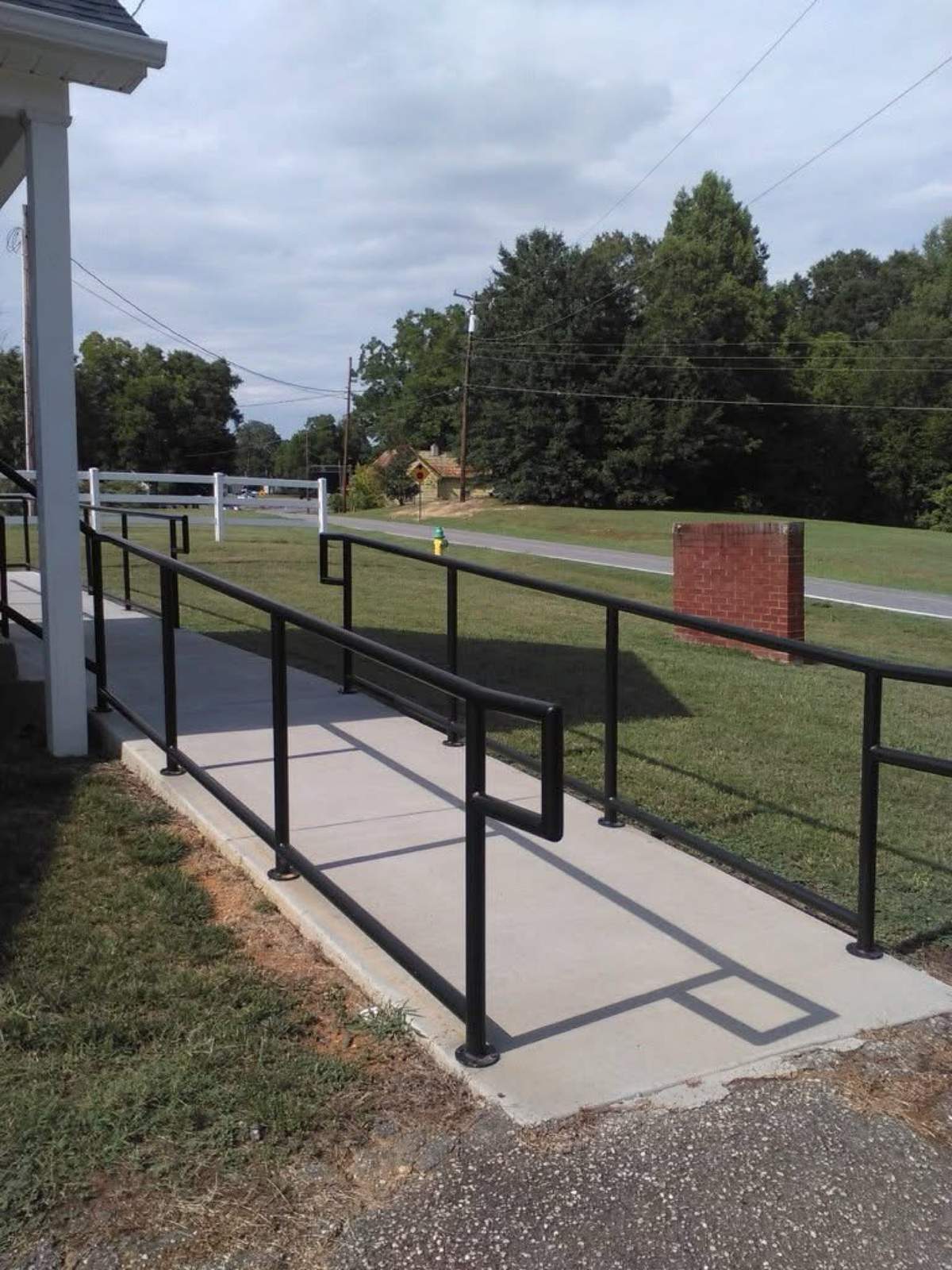Black steel ADA-style handrails along a concrete ramp