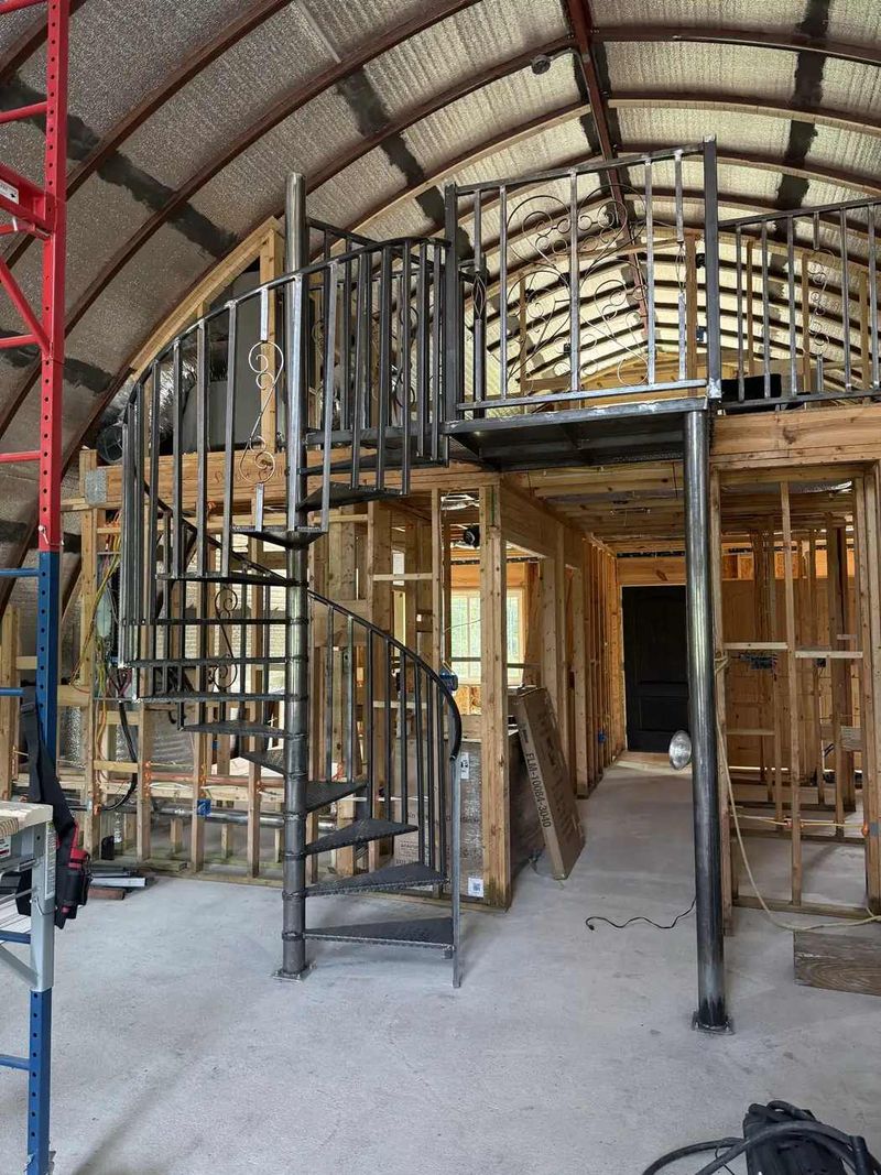 Custom steel spiral staircase with decorative scroll railings, mezzanine guardrail and steel support column