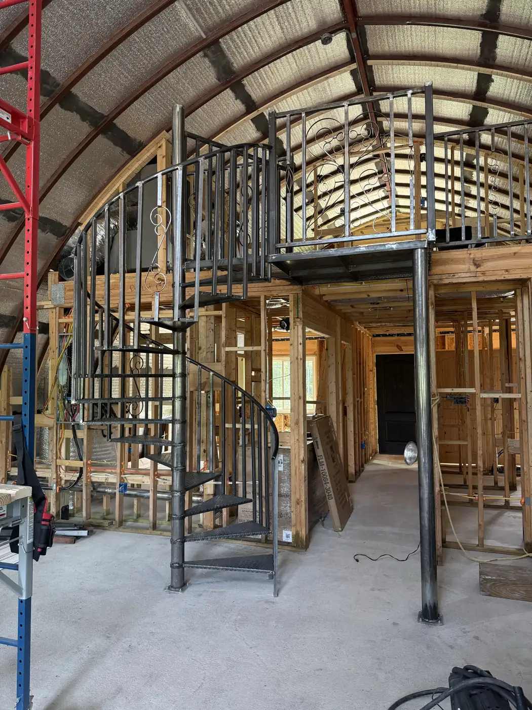Custom steel spiral staircase with decorative scroll railings, mezzanine guardrail and steel support column
